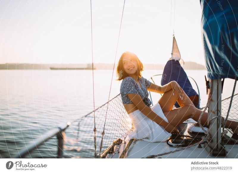 Stylish female tourist resting on yacht and looking away woman admire sea sailboat traveler sunset vacation cruise holiday style portrait trendy trip young