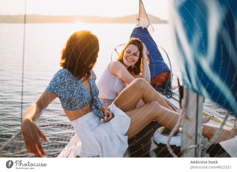 Happy ladies chatting during cruise on sea at sunset women sailboat friend summer vacation together yacht happy smile talk relax trendy young holiday cheerful