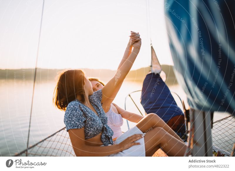 Content traveling girlfriends holding hands on yacht at sundown women cruise sea sailboat sunset friendship together holiday vacation trip summer young trendy
