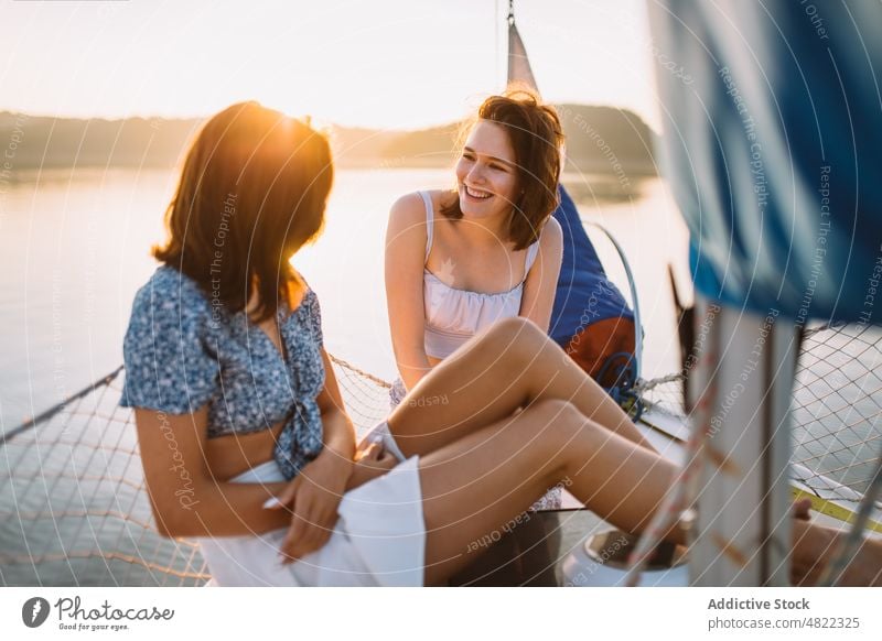 Happy ladies chatting during cruise on sea at sunset women sailboat friend summer vacation together yacht happy smile talk relax trendy young holiday cheerful