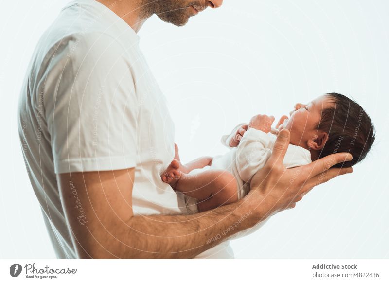 Crop unrecognizable father holding cute baby against white background man love newborn adorable childcare together innocent embrace babyhood male young infant