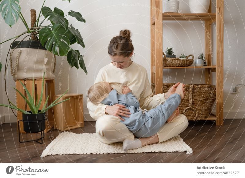 Delighted mother breastfeeding cute little song having fun on floor woman child bite motherhood together positive parent tender female young casual kid boy love