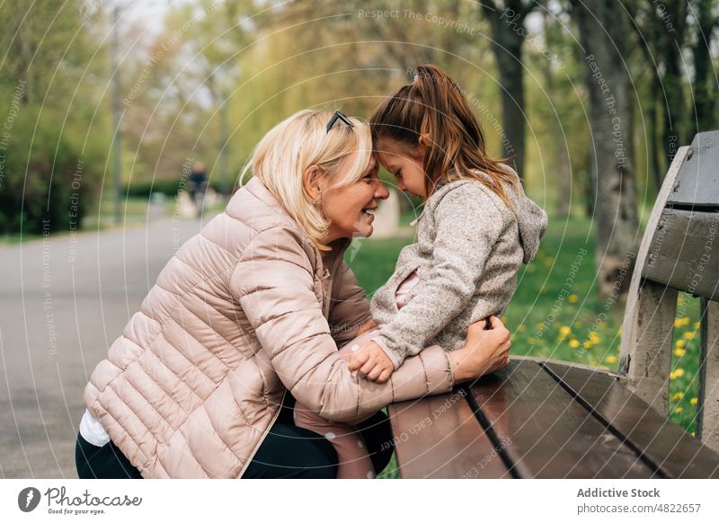 Mature grandma embracing cute girl in park woman child granddaughter embrace love grandmother relationship happy bonding together mature kid warm clothes tree