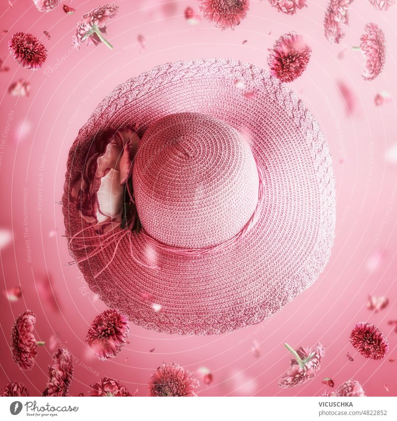 Sun hat with falling flowers and petals at light pink background. Summer levitation sun hat summer concept blossom clothing accessories front view design bloom