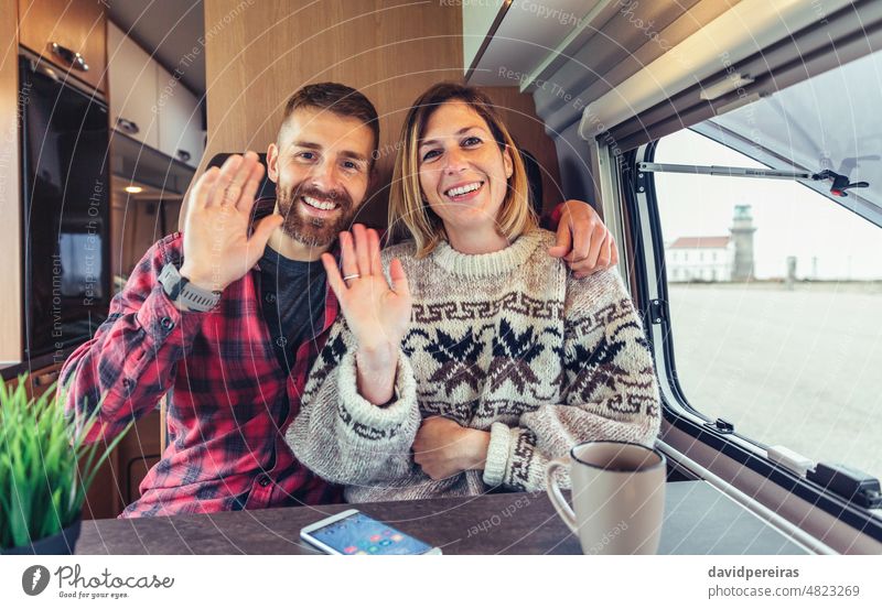 Couple waving looking at camera on video call from their camper van happy couple looking camera smiling travel hand person talking videoconference online