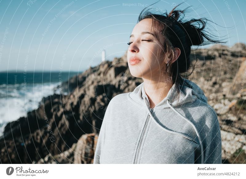 Young woman inspiring while resting near lighthouses on the shore line. Relaxing and chilling against stress and anxiety. Mental health on young people concept. Copy space image with light concept