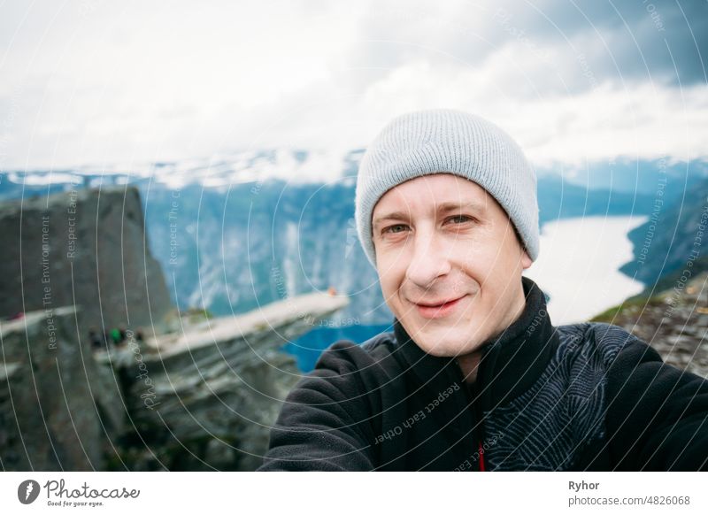 Young Tourist Taking Selfie Against The Backdrop Of The Norwegian Mountains Trolltunga - Troll Tongue adventure background beautiful caucasian cute europe