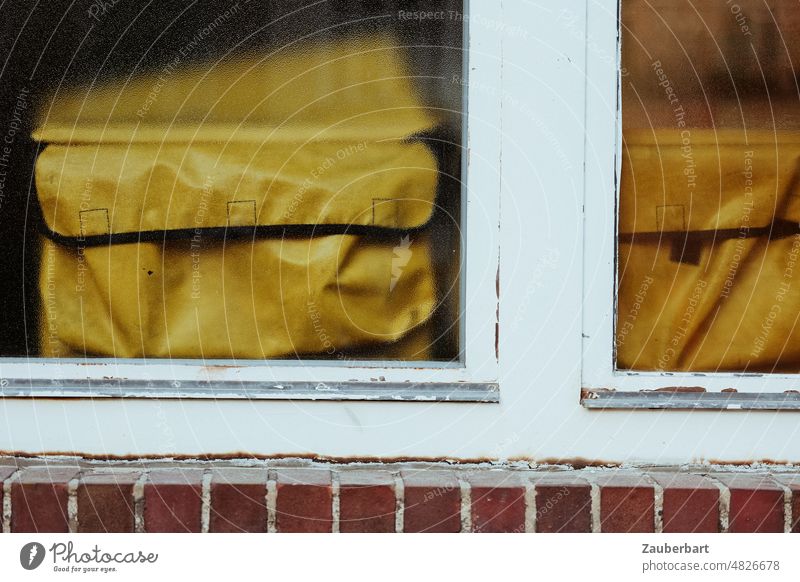 Yellow parcel bags of the post office behind white window frame in front of ledge of bricks Package bag Mail Letter post Frame Window frame White Cornice