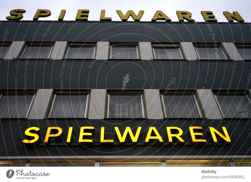 Yellow neon sign on a traditional shop for toys in a typical post-war building in the evening in the Bornheim district of Frankfurt am Main in the German state of Hesse