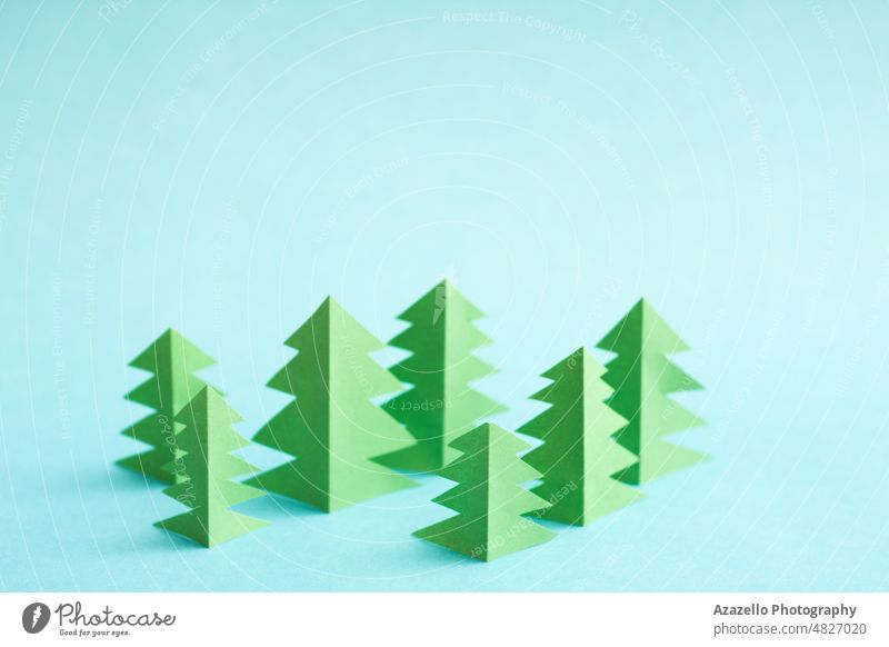 Green paper trees on blue background with free copy paste space. Origami forest abstract concept conceptual creative design ecological ecology environment
