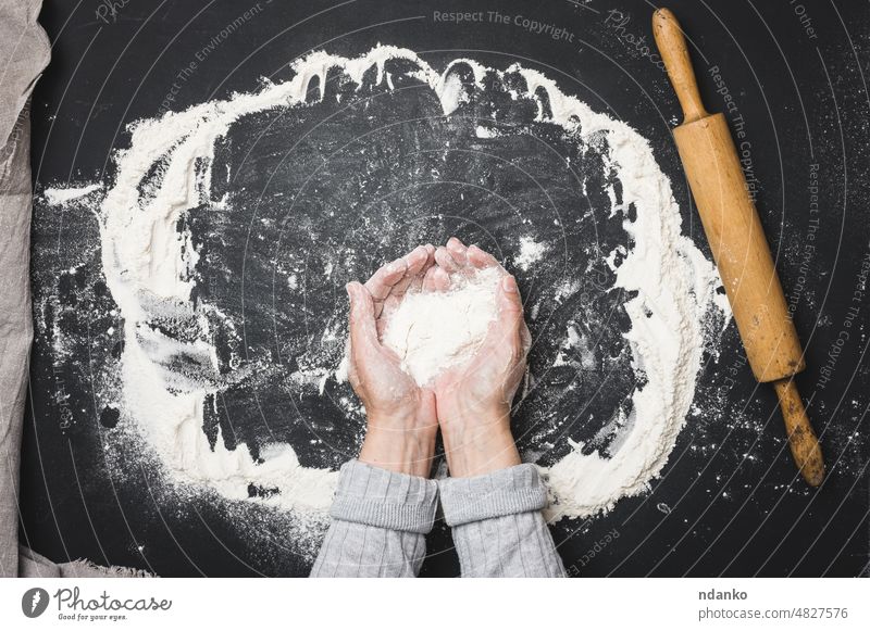 two female hands hold a handful of white wheat flour on a black table, top view baker bakery baking bread cook cooking cuisine dough food heap holding indoor