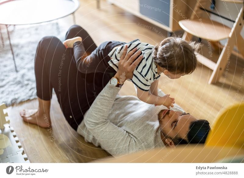 Dad playing with his little son at home adult affection baby bonding boy candid care child childhood domestic enjoying family fun happiness happy house indoors