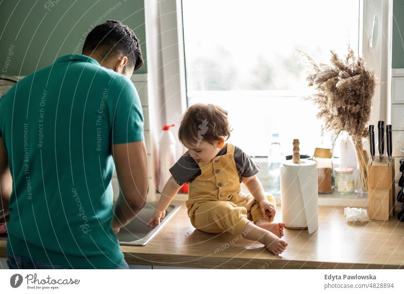 Father with his young child in the home kitchen adult affection baby bonding boy candid care childhood domestic enjoying family fun happiness happy house