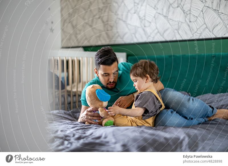 Dad playing with his little son at home adult affection baby bonding boy candid care child childhood domestic enjoying family fun happiness happy house indoors