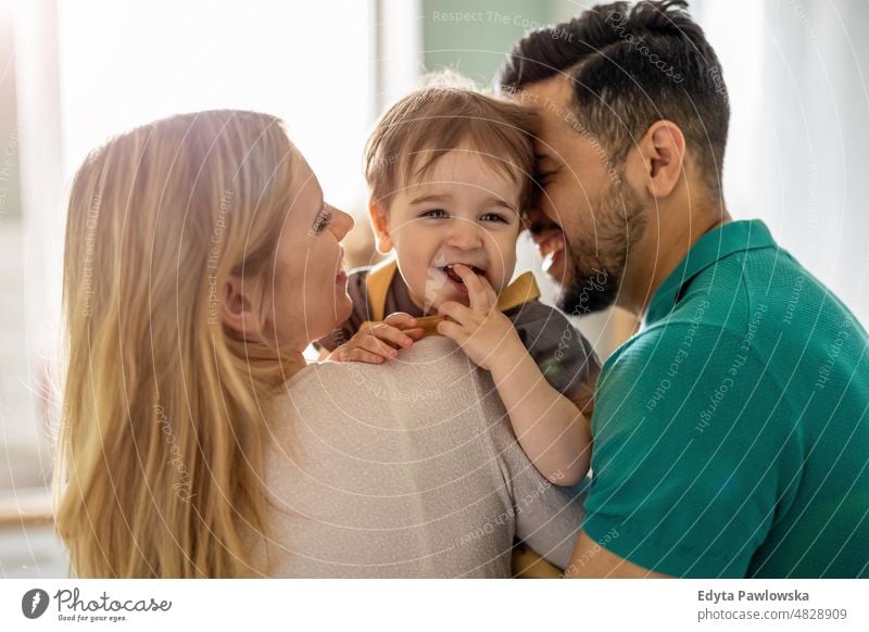 Young parents playing with their child at home weekend playful mom mother father domestic positive leisure enjoying adult affection baby bonding boy candid care
