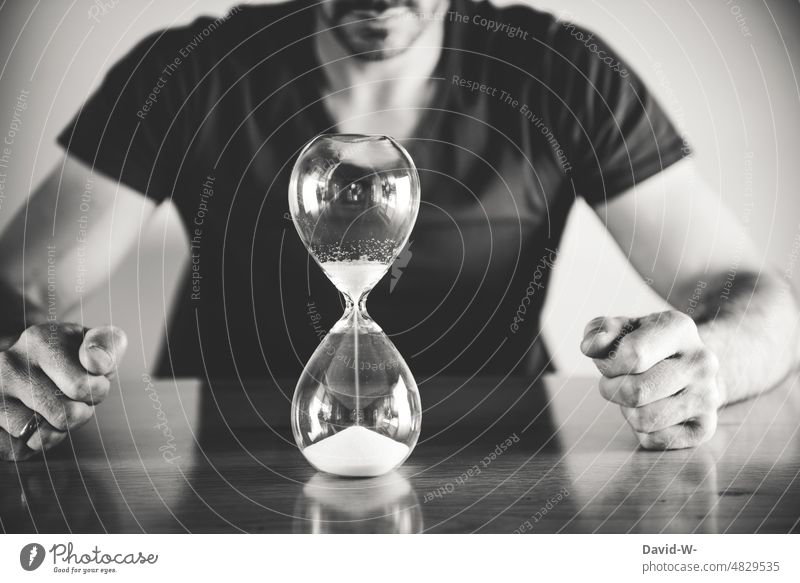 Time is running out - man in front of an hourglass Hourglass Man time pressure expire Period of time Sand Clock Transience time management concept Wait