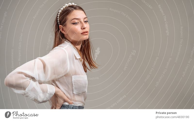 portrait of a young woman in her 20s in casual clothes posing against a gray studio background. People lifestyle concept. Mock up copy space. Standing with arms akimbo on waist