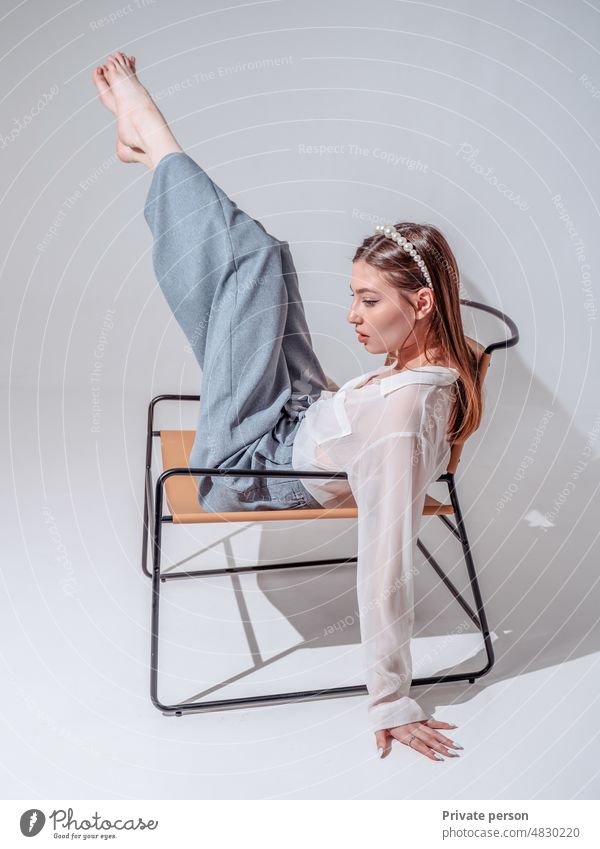 Feet up. Casual young woman sits barefoot on a comfortable armchair, relaxes, raises her legs. vertical. legs up sitting carefree relaxation calm freedom
