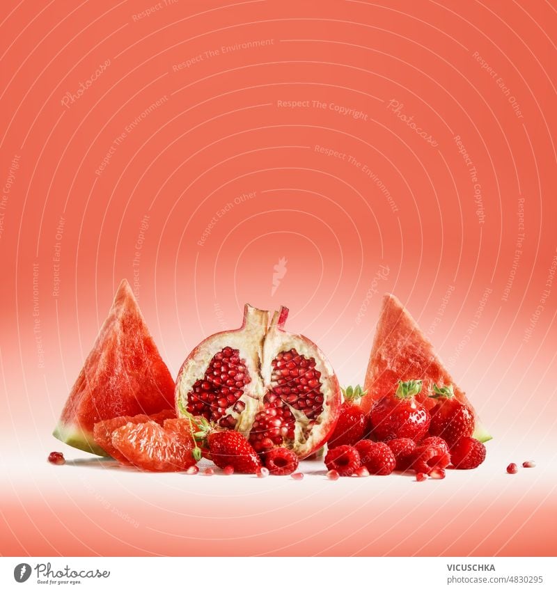 Red fruits selection with watermelon, pomegranate, strawberries and raspberries at bright background red delicious healthy sweet summer ingredients front view