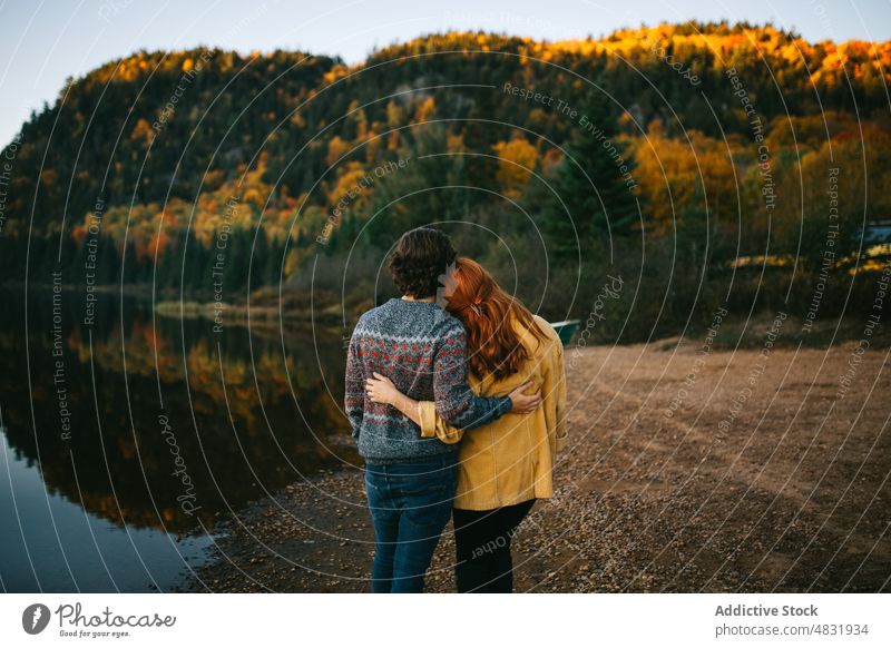 Anonymous loving couple cuddling on lake shore on autumn day embrace forest trip love admire hug travel relationship romantic landscape nature lakeside