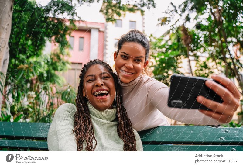 Happy diverse girlfriends taking selfie on bench women park smartphone laugh together happy smile female multiracial multiethnic black african american hispanic