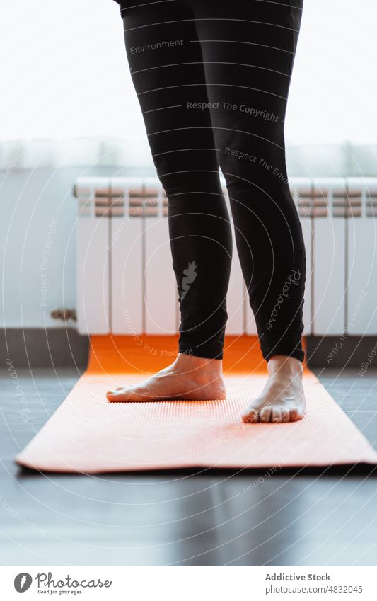 Crop barefoot pensioner stretching legs standing on mat during fitness training woman exercise home morning female gymnastic leggings elderly aged senior