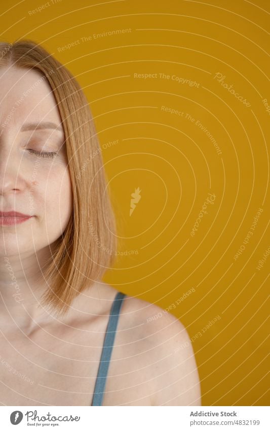 Crop tranquil young lady with closed eyes in yellow studio woman eyes closed calm model portrait personality peaceful feminine recreation human face facial