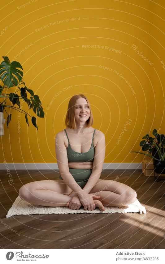 Happy female sitting in Padmasana pose and smiling during yoga session woman lotus pose padmasana smile positive wellness healthy lifestyle stress relief