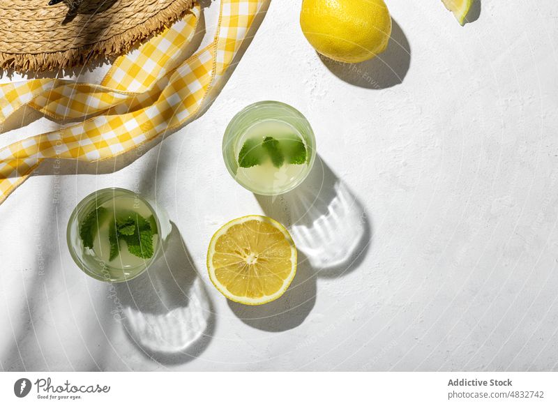 Flat lay of summer concept composition lemon fresh natural healthy creative organic glasses drinks hat yellow color shadow sunlight mint bright fruit vivid food