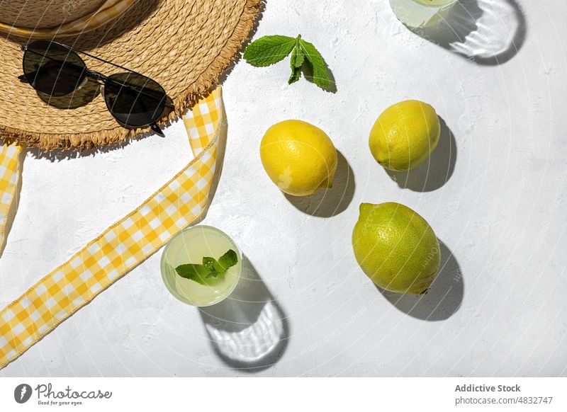 Flat lay of summer concept composition lemon fresh natural healthy creative organic sunglasses drinks hat yellow color shadow sunlight mint bright fruit vivid