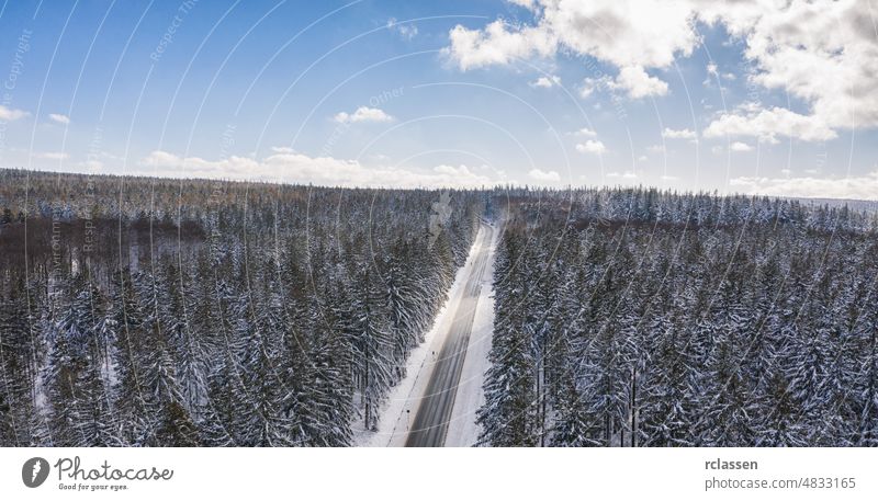 Aerial view of cars driving by the road through the forest covered by snow in winter and cloudy sky, including Copy space drone aerial sunset snowy sunlight
