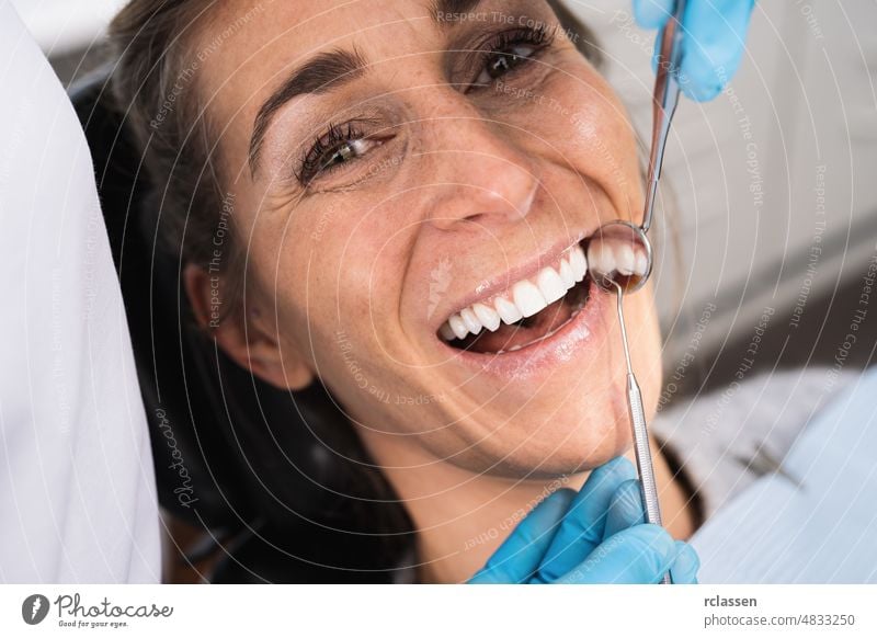 Dentist examining a female patient's teeth in the dentist. dental dentistry care health smile white teeth doctor mirror mouth hygiene whiten clinic tool