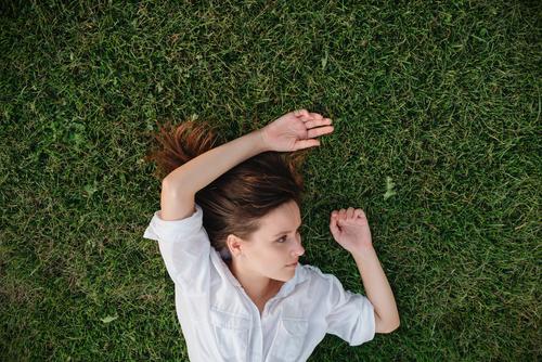 shot of woman lying on green grass above adult caucasian daydreaming female garden girl hands happy leisure lifestyle meadow nature outdoors outside park