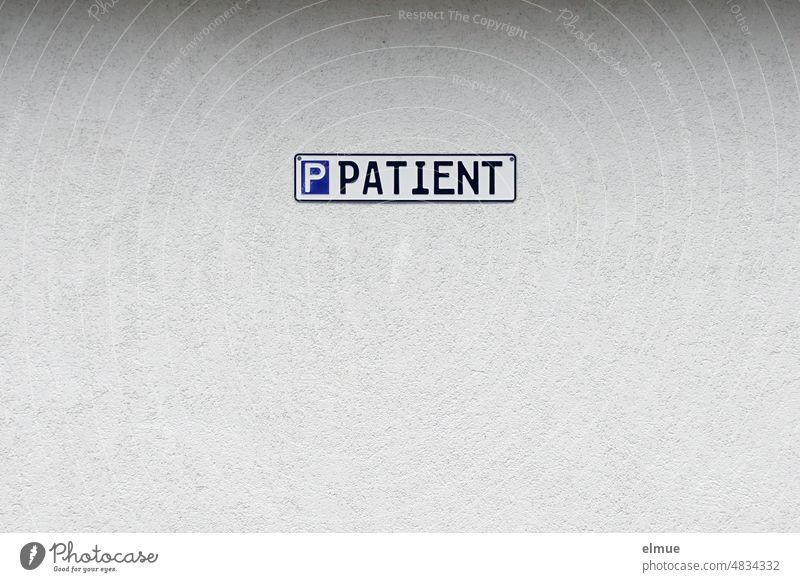 A sign in the form of a car license plate with the inscription P Patient on a gray plastered wall / parking lot Parking lot Patient parking Reserved