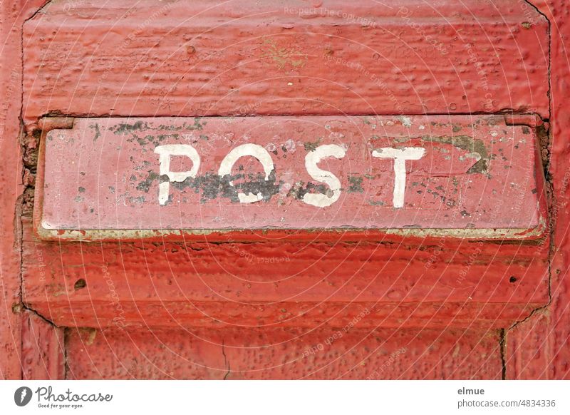 On the red mail slot on an old red-painted wooden door, handwritten in white capital letters is POST Wooden door door slit Mail slot timeslot Postal slot