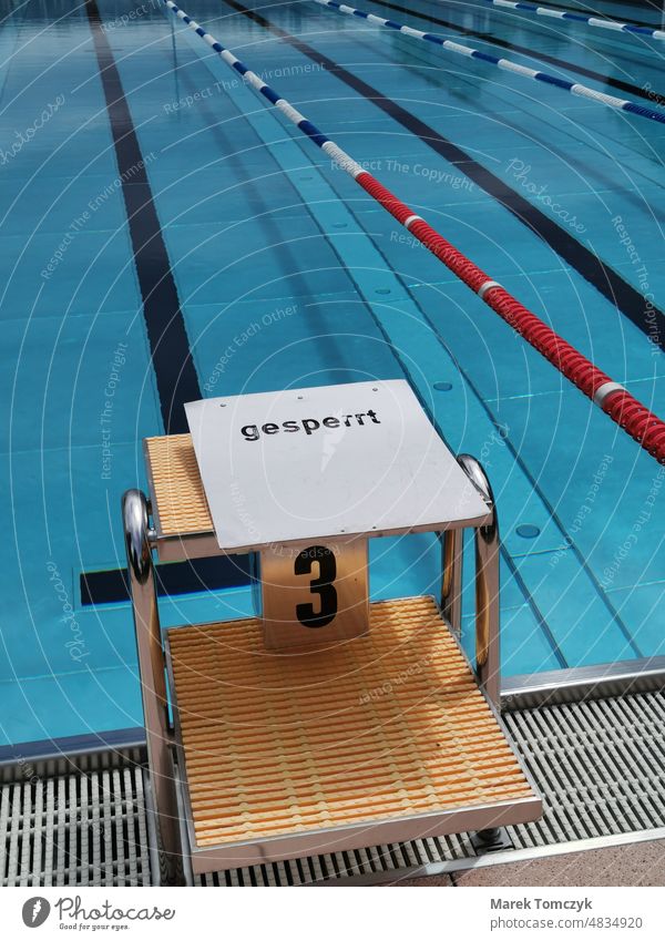 Blocked starting block in deserted swimming pool. Clear water without waves. Swimming pool Open-air swimming pool Starting block (track and field) Barred