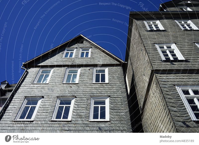 Old facade with shingles of slate in gray and anthracite against blue sky in the sunshine in the alleys of the old town of Marburg on the Lahn in Hesse Old town
