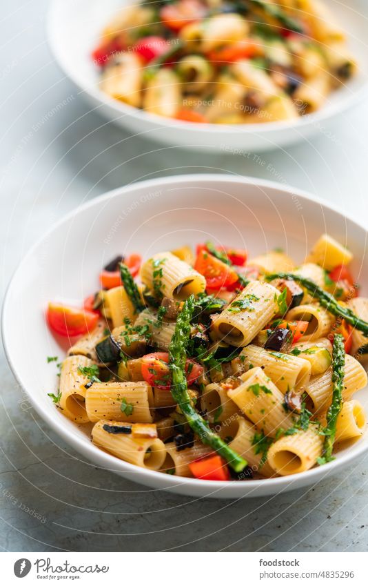Pasta salad with grilled vegetables, zucchini, eggplant, asparagus and tomatoes. Summer background basil cherry colorful cooked dinner dish eating food fresh