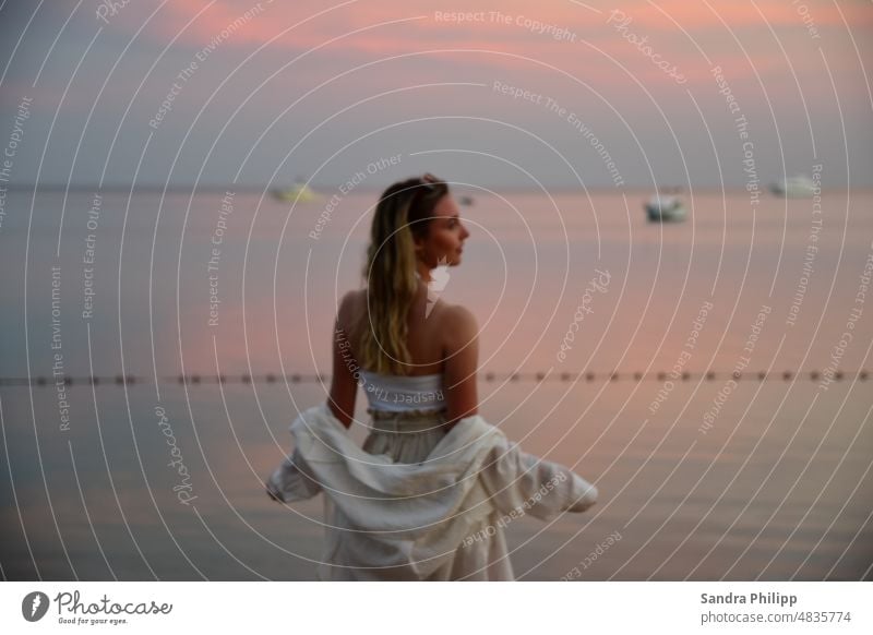 Young blonde woman in summer outfit looks at the sea Young woman Blonde La Long-haired pretty Exterior shot Feminine Hair and hairstyles Ocean Water Sunset