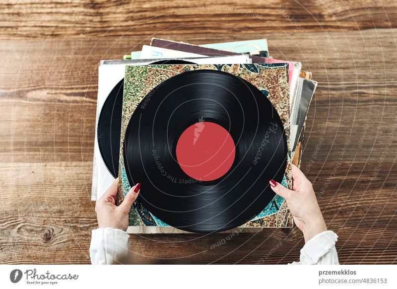 Playing vinyl records. Listening to music from vinyl record player. Retro and vintage music style. Woman holding analog LP record album. Music passion listening