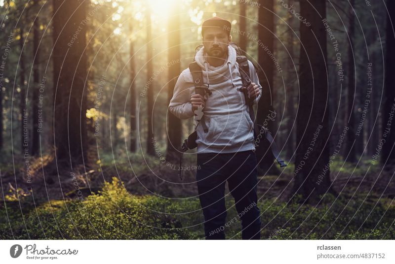 Portrait of a young hiker with backpack in the forest at a summer day nature landscape spring sun sunlight tree needlewood idyllic environment sunset trunk