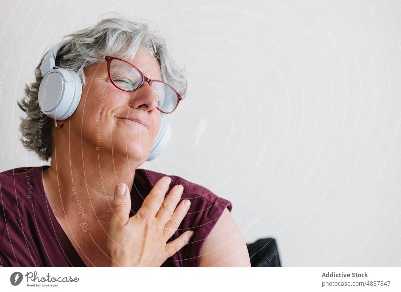 Satisfied senior lady listening to music in headphones with closed eyes woman eyes closed meloman enjoy song audio content positive favorite melody female