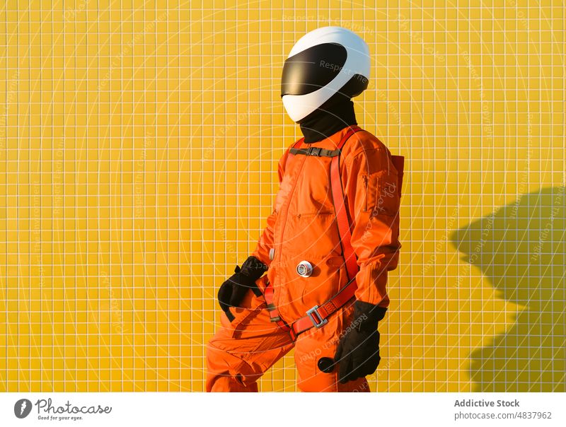 Confident cosmonaut against yellow wall astronaut spacesuit confident success costume concept sand beach explore uniform helmet brave safety spaceman aspiration