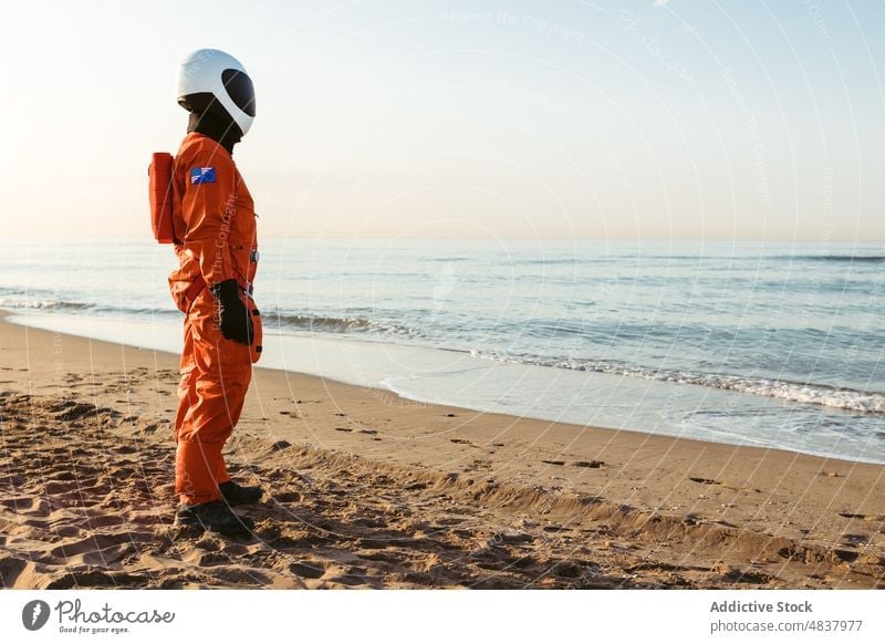 Spaceman standing standing and admiring sea spaceman beach astronaut admire evening rest concept futuristic resort sand vacation spacesuit helmet cosmonaut