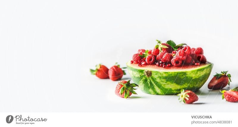 Banner with watermelon half filled with strawberries and raspberries on white background. banner red fruit healthy summer food front view berry delicious fresh
