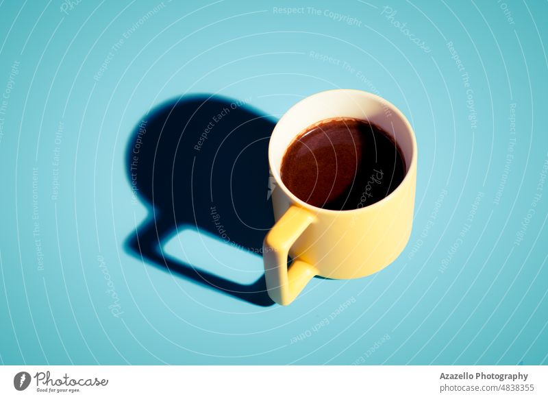 Fresh Turkish coffee in a yellow cop with hard shadow on blue background. still life turkish bright beans active aroma beverage black breakfast brewed brown