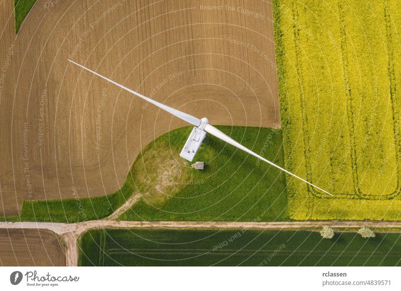 Wind turbines and agricultural fields on a summer day - Energy Production with clean and Renewable Energy - top view shot power windmill grid aerial drone