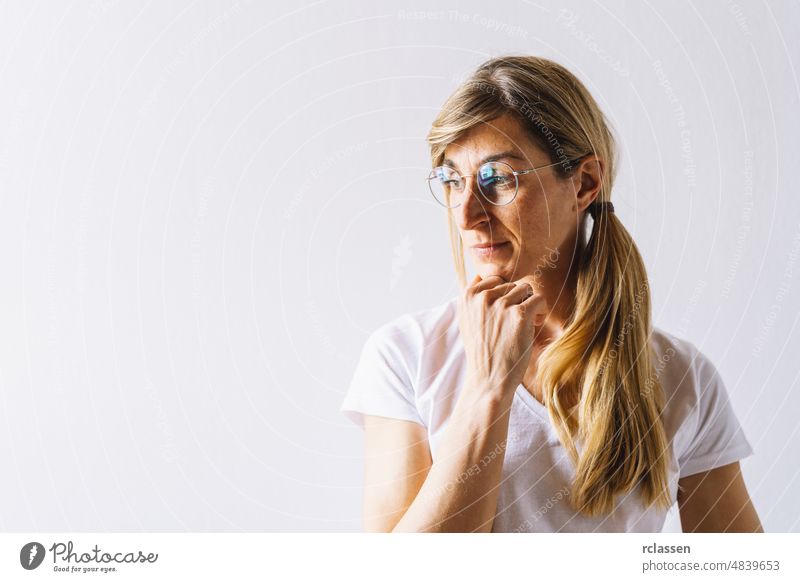 portrait of young woman thinking looks left hand on chin, thinking positive, with copyspace for text business person businesswoman hipster adult beauty face