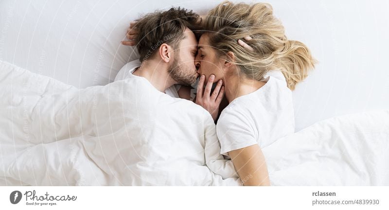 Love story. couple kissing lying on the bed in a light room at the morning. Love, happiness, family. Top view shot sex sexy man woman male naked above bedroom
