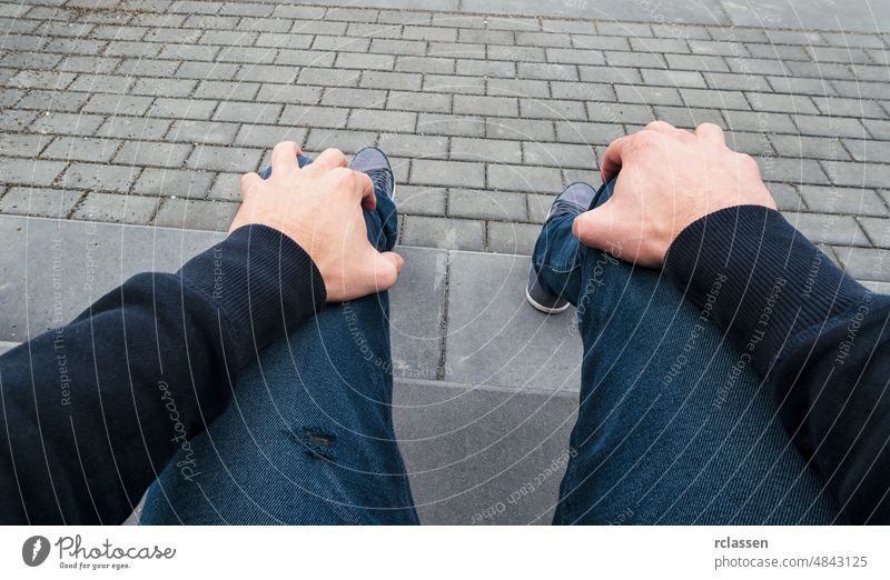 man sits on a curbstone and waits nervous for somebody, Point of view shot pov people lifestyle point summer way caucasian close-up young first person view